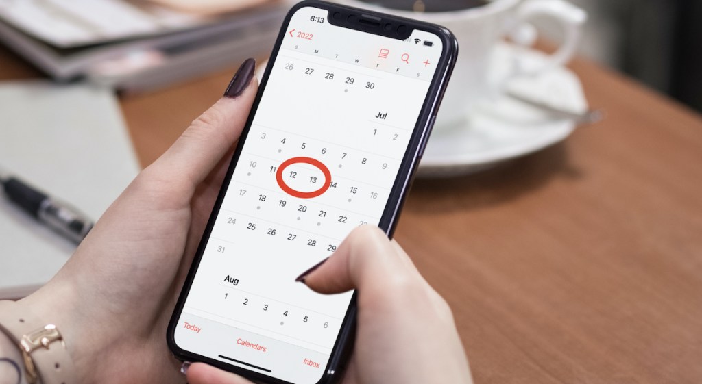 woman holding phone with calendar on screen and prime dates circled in red