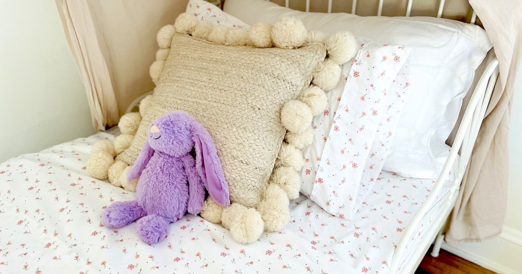 childs bed with purple bunny and huge cream pom pillow
