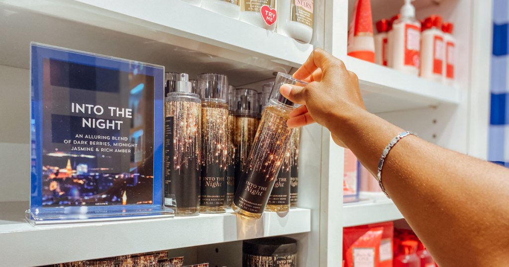 woman grabbing bath and body works fragrance mist from store shelf