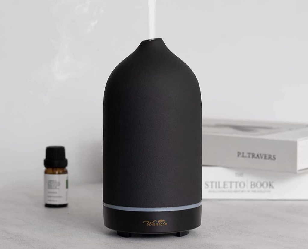 black stone essential oil diffuser on table with steam coming out of top