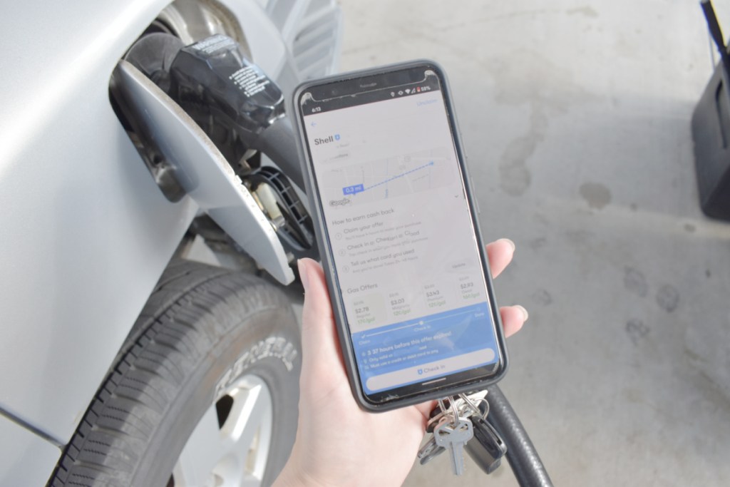 hand holding phone with GetUpside app in front of car getting gas