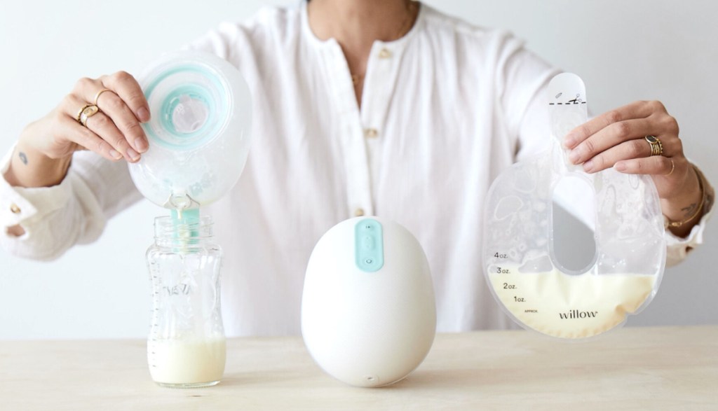woman holding up bag of breast milk with willow hands free breast pump on display