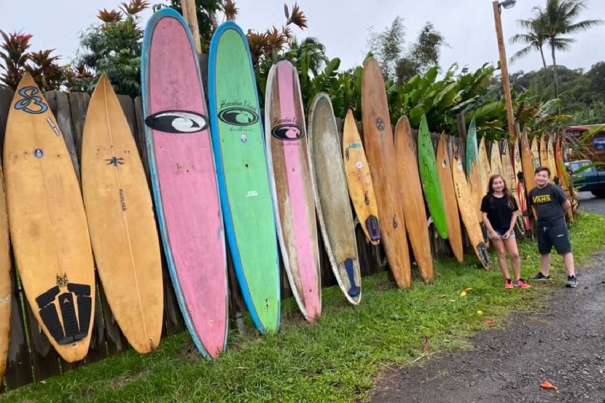 hawaii vacation surf boards lined up on side of the road beside two kids