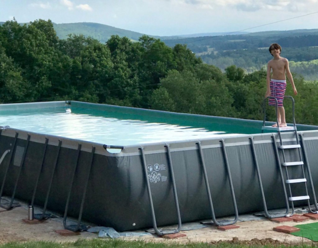 kid standing on ladder from above ground pool