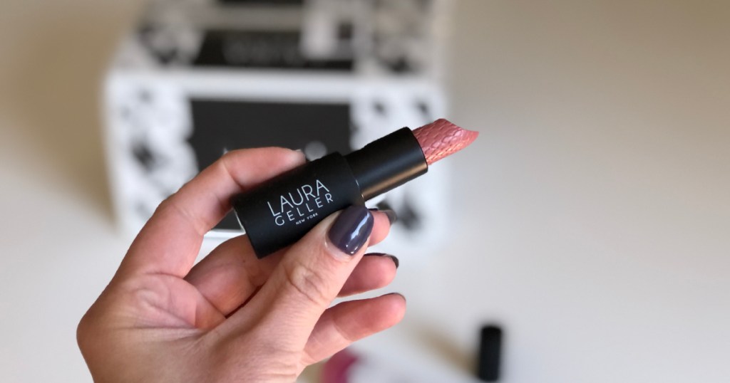 hand holding tube of laura geller lipstick