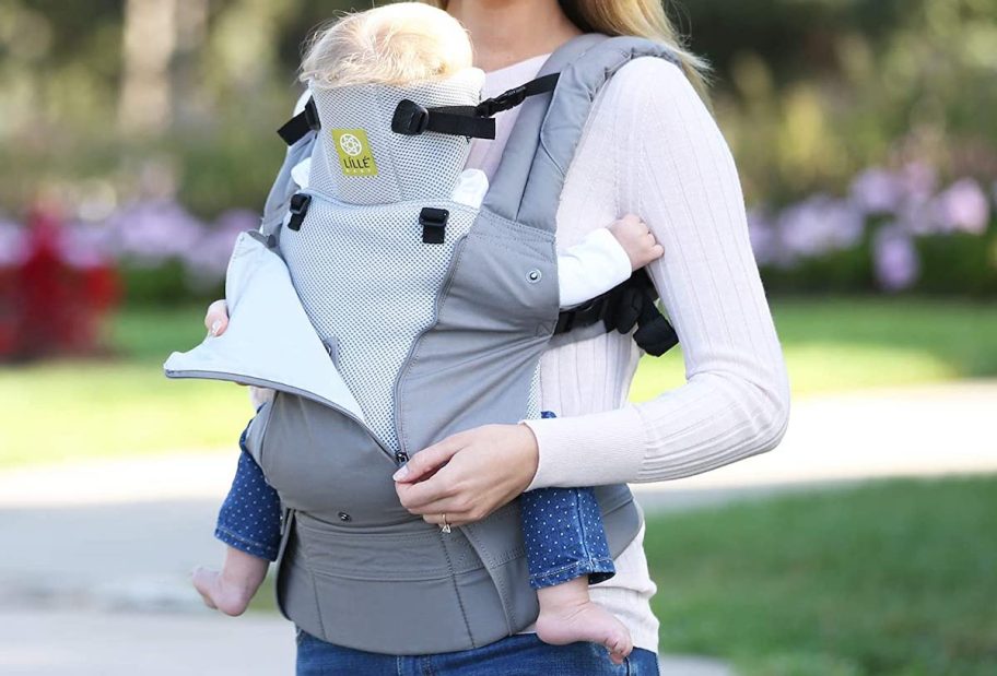 woman holding baby with gray baby carrier outside