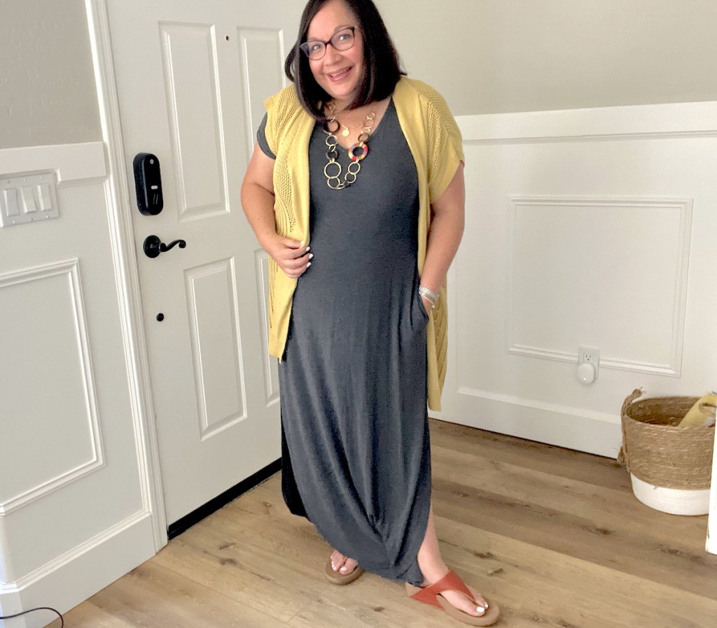 woman wearing gray maxi dress and yellow cardigan smiling in foyer