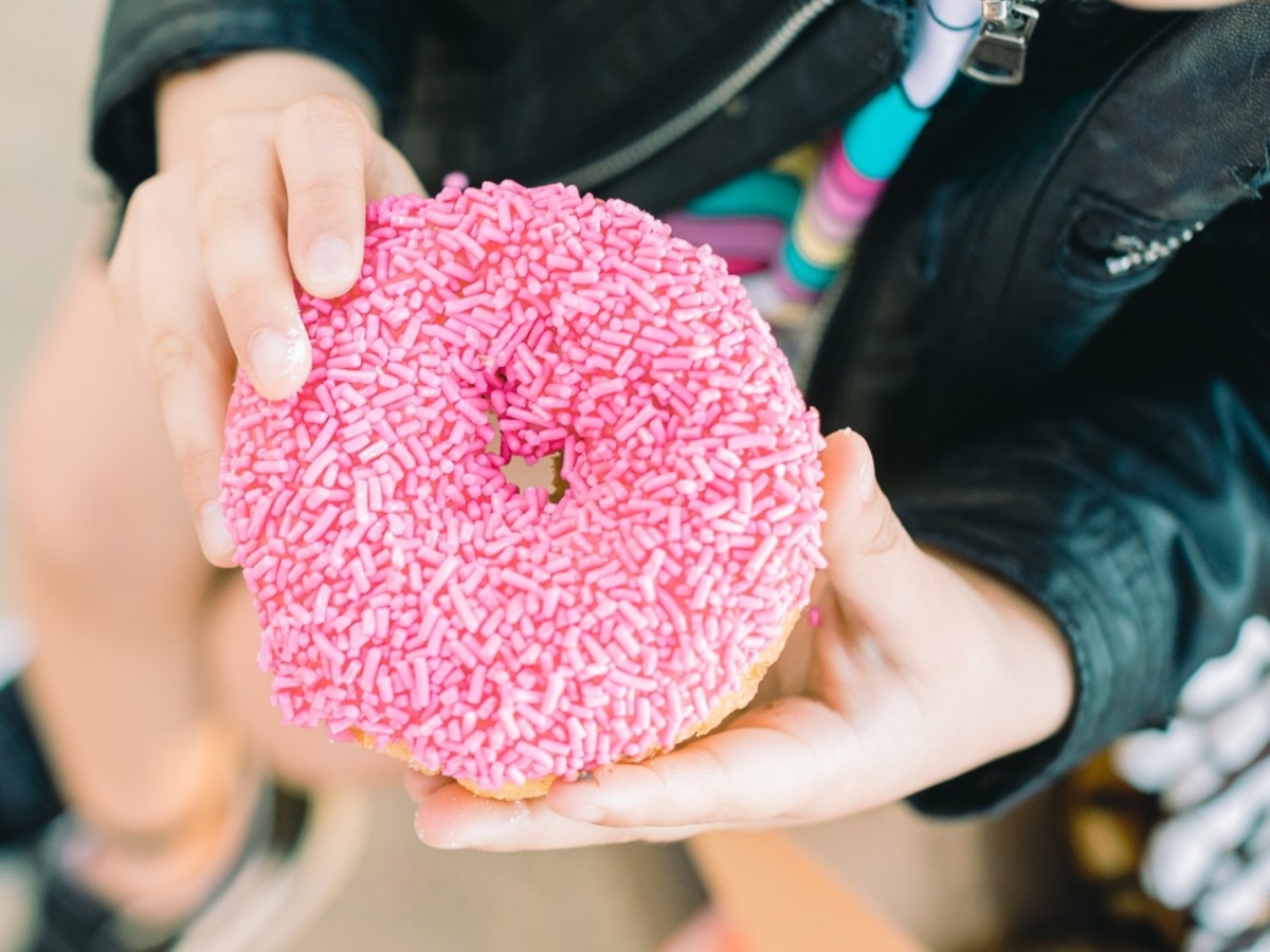 holding a pink donut with sprinkles