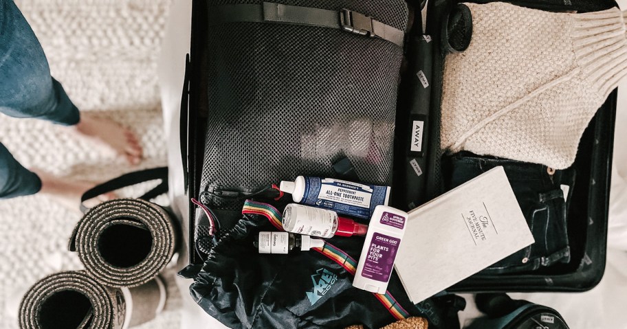 suitcase with various toiletries on top for travel packing hacks