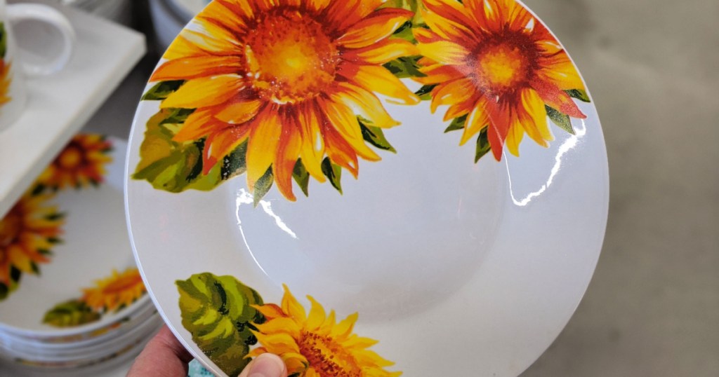 hand holding up a plate with sunflowers