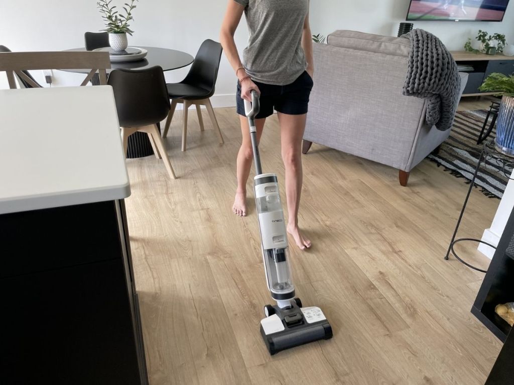 woman doing her own house cleaning services pushing tineco mop on wood floor