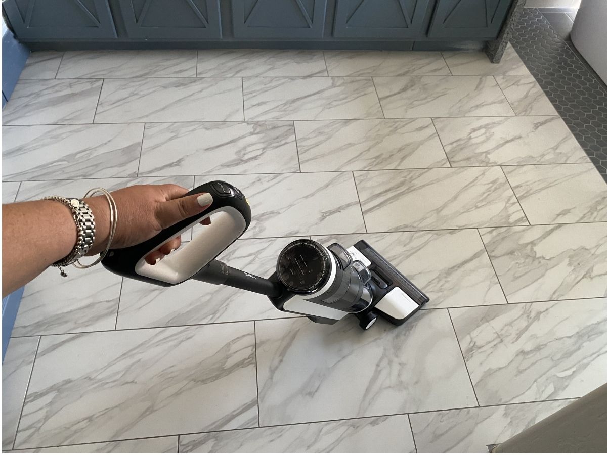 woman using vacuum on tile floor