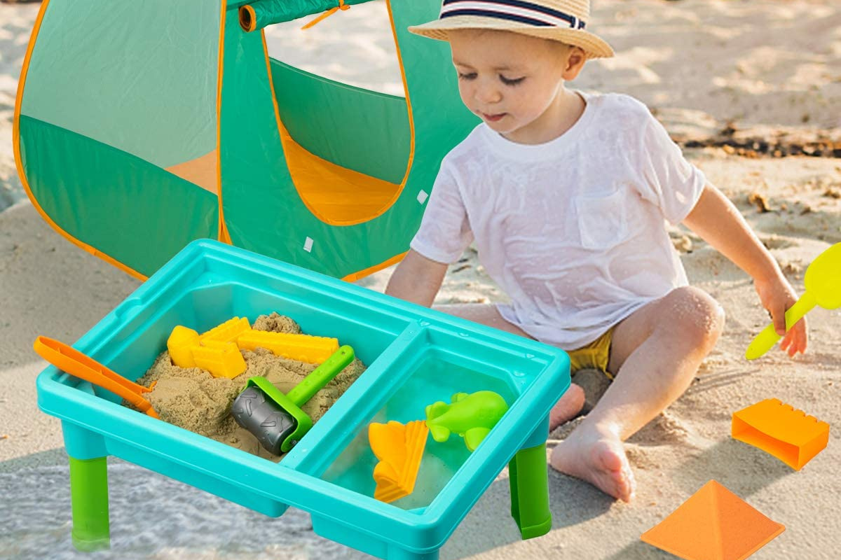 child playing with water table in front of tent in the sand