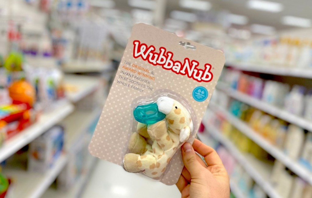 hand holding baby pacifier wubbanub in store aisle