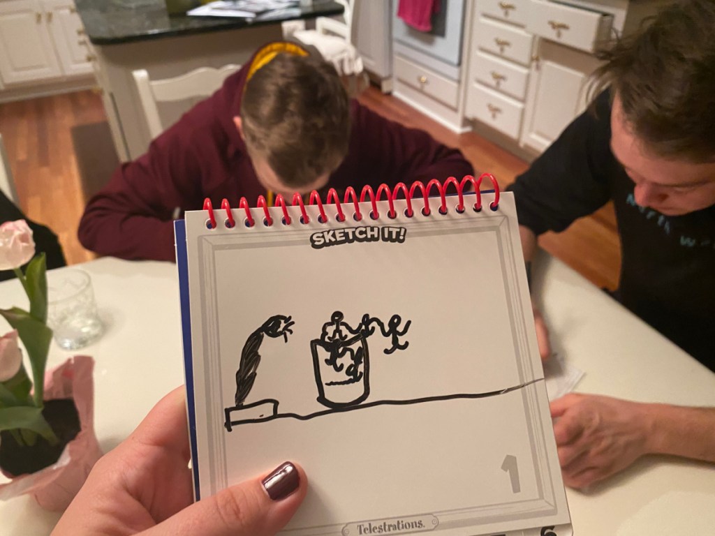 hand holding dry erase notebook for Telestrations board game