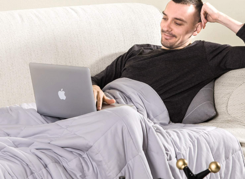 man sitting with a computer and blanket