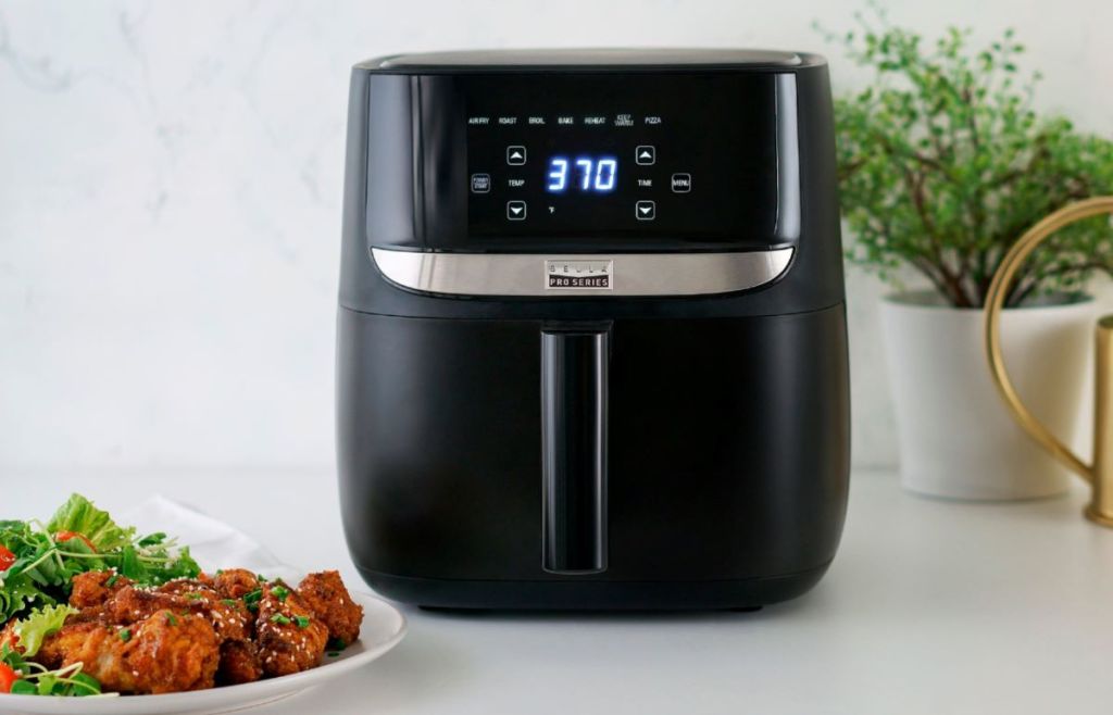 digital air fryer with a plate of food next to it