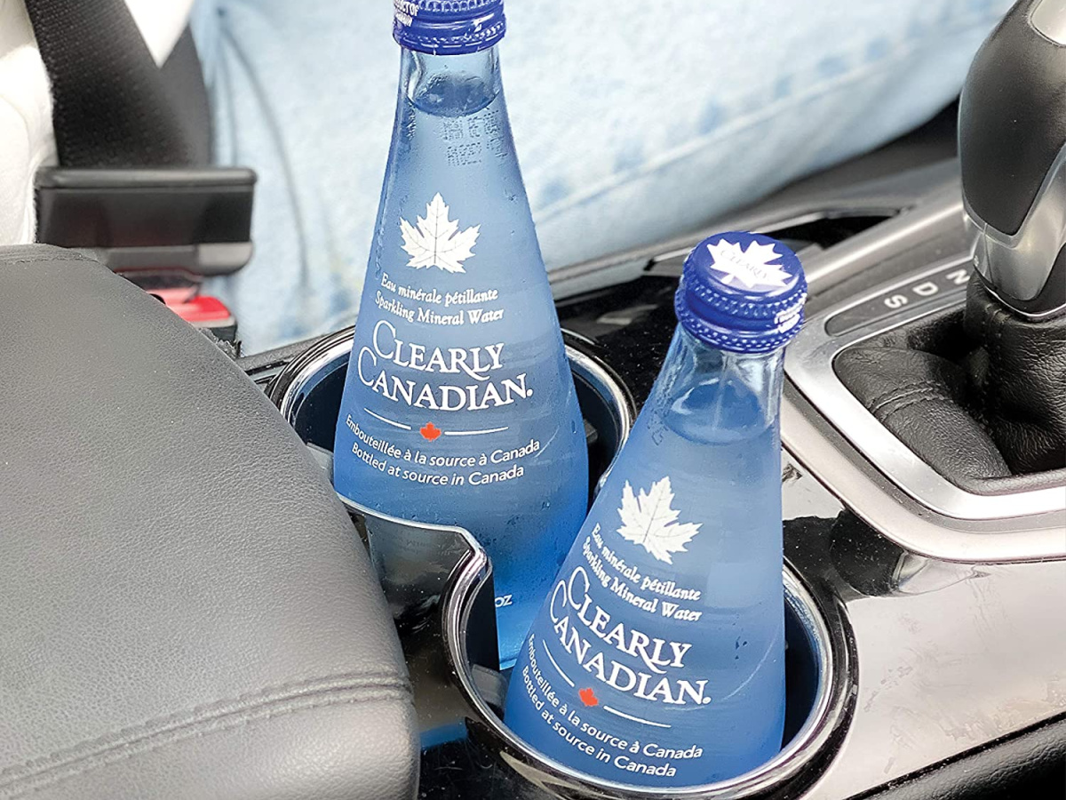 two glass bottles of clearly canadian sparkling water in a car cupholder