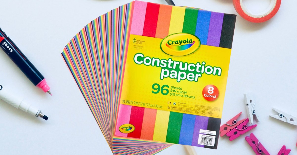 pack of multicolor crayola construction paper fanned out over pens and mini clothes pins