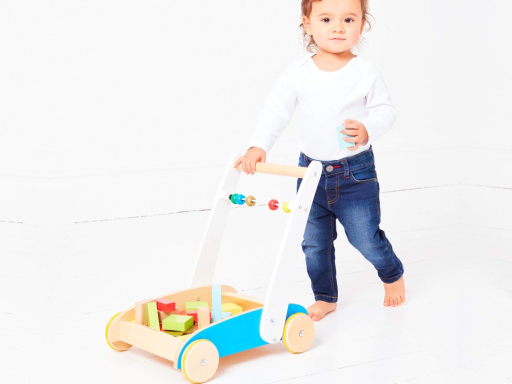 small child pushing a wooden cart with wooden blocks