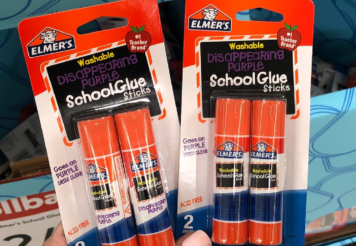 hand holding two packs of elmers glue sticks in store