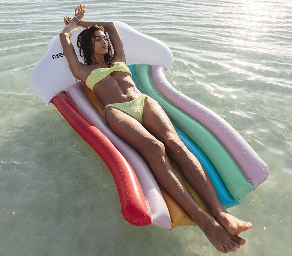 woman laying on a rainbow pool float
