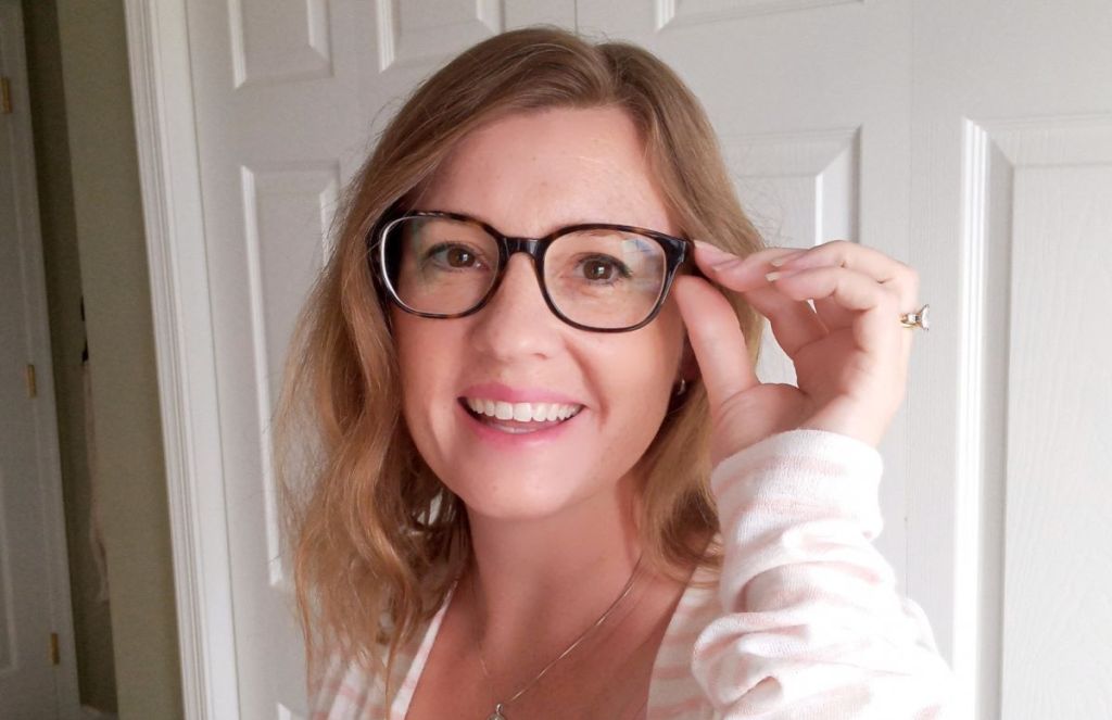 woman holding a pair of glasses she's wearing