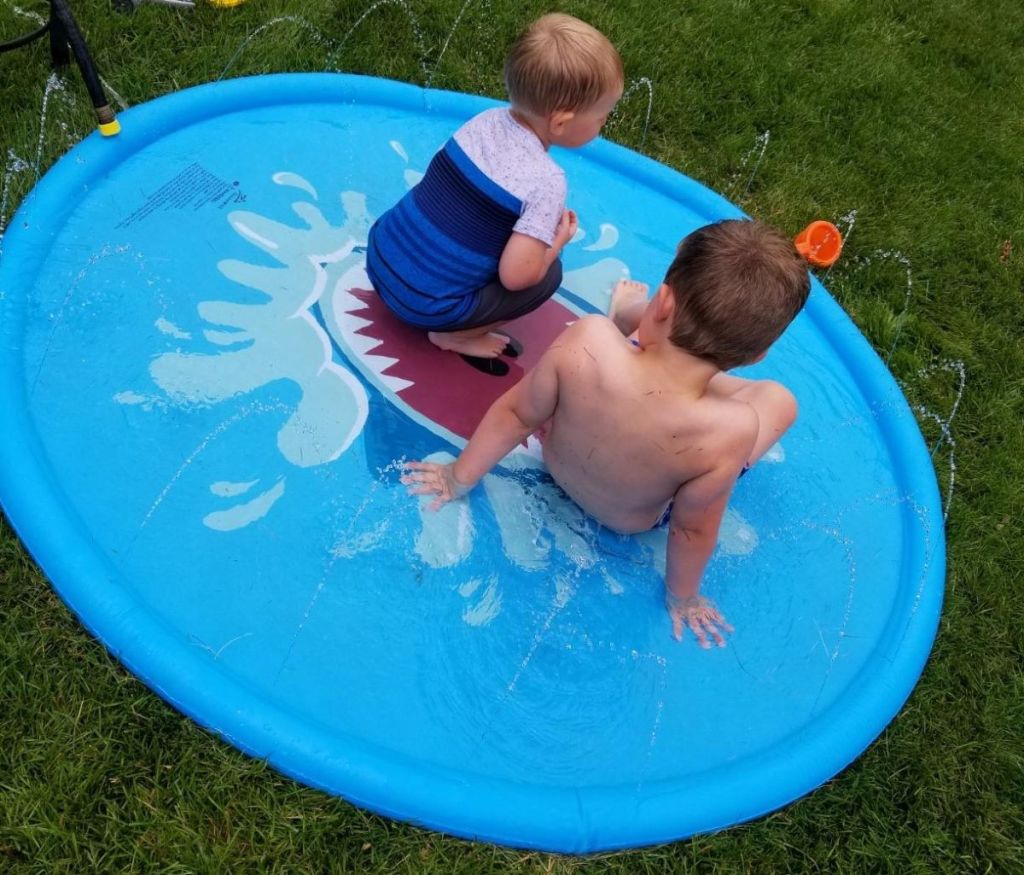 two kids sitting in a sprinkler