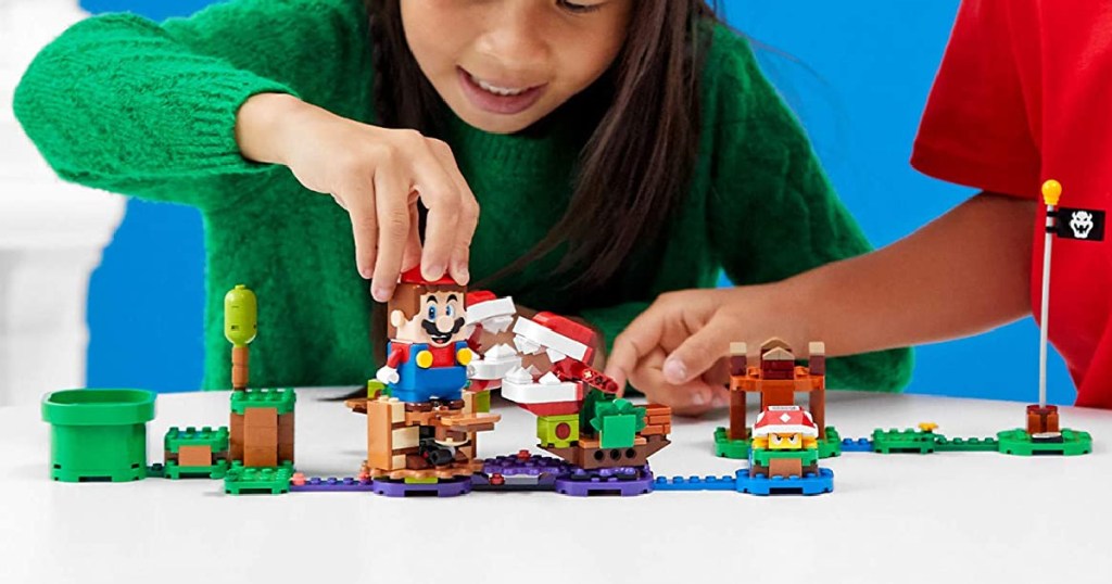 two kids playing with a Super Mario LEGO set