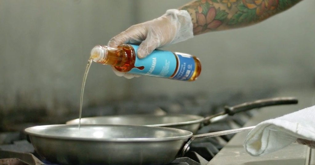 hand pouring oil from bottle into sautee pan