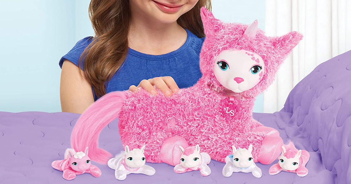 girl wearing a blue shirt petting a pink llamacorn toy on a purple bed with llamacorn babies