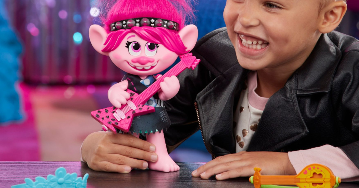 little girl playing with pink troll doll holding guitar