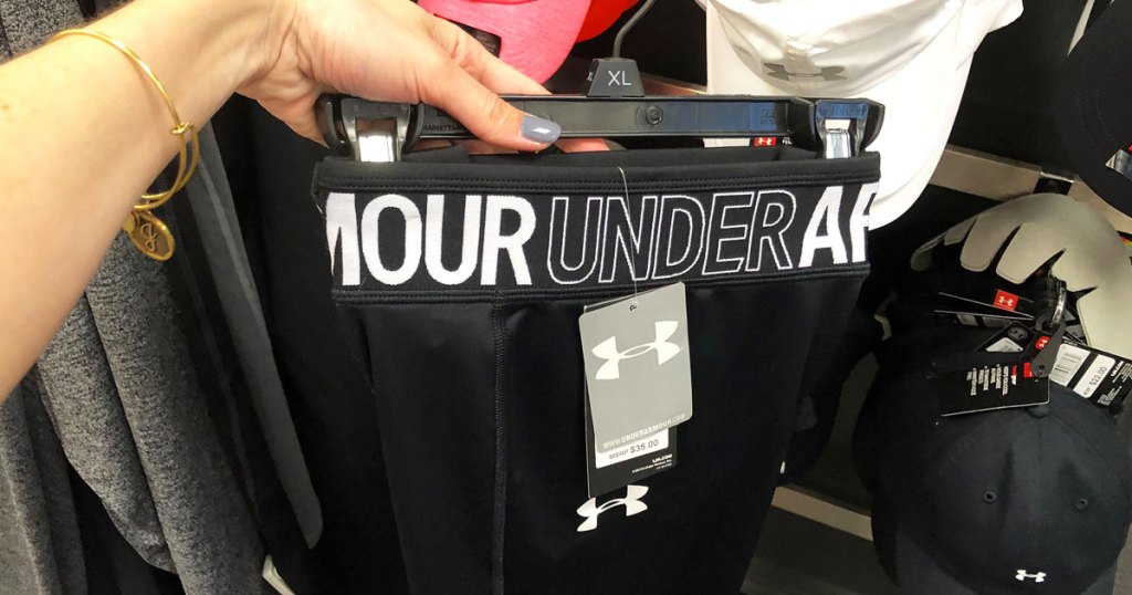 woman holding up black pair of under armour shorts on hanger
