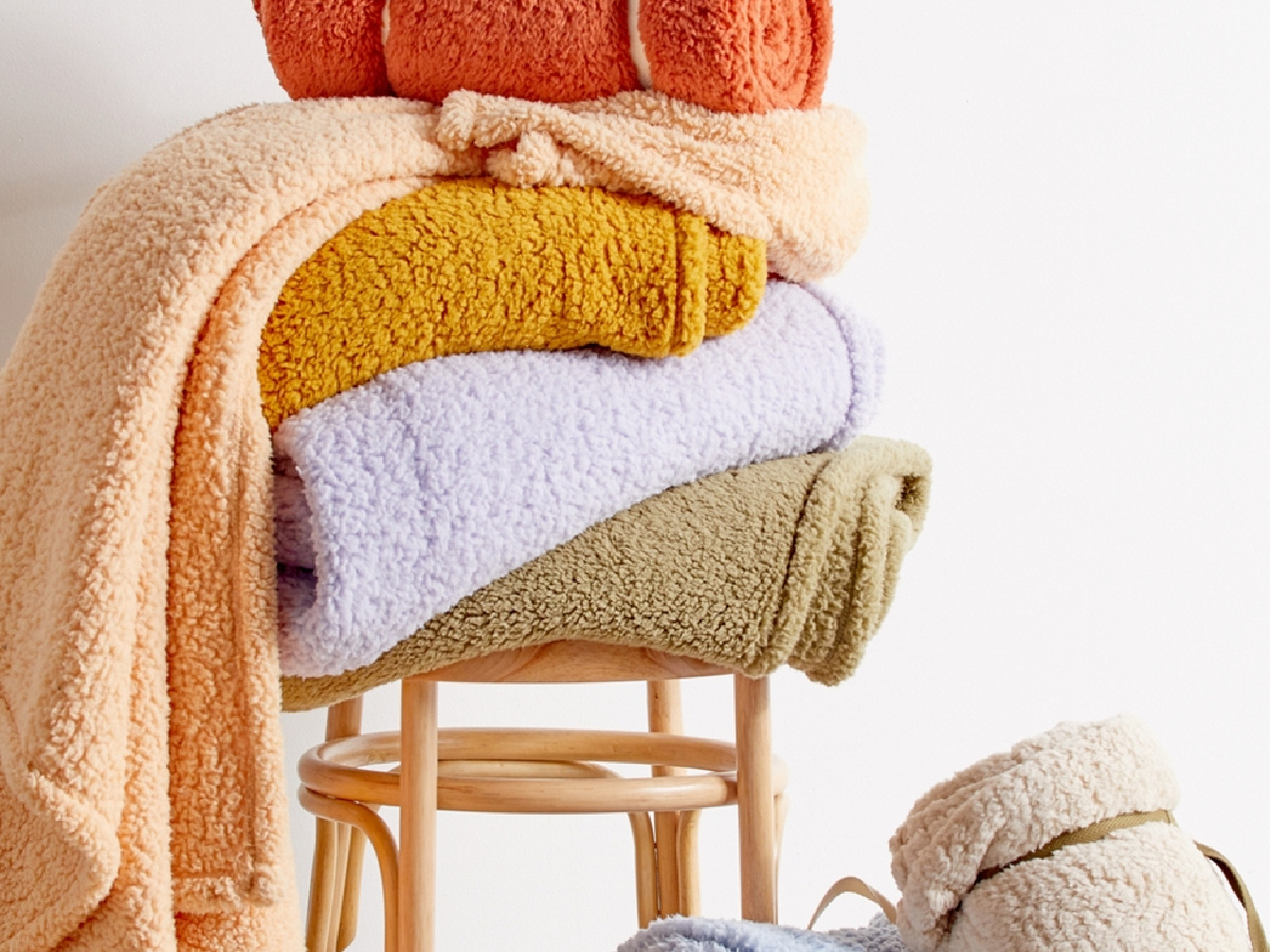 stack of cozy blankets on a wooden stool