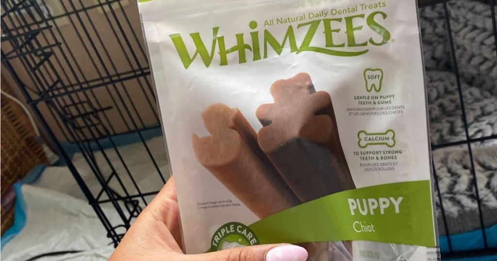 woman's hand holding two bag of puppy dental treats