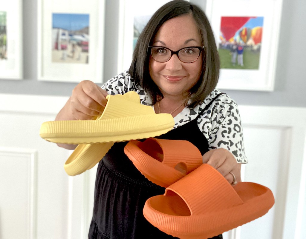 woman holding yellow and orange pair of bathroom slippers 