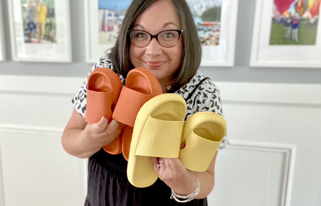 woman holding yellow and orange pair of bathroom slippers