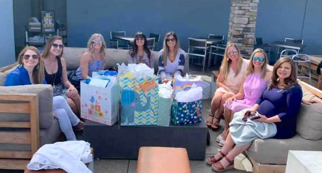 woman sitting outside with sunglasses with baby shower gift on table in middle