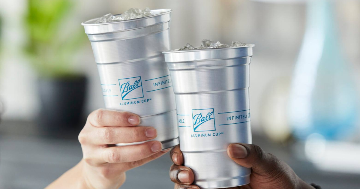 two hands each holding up an aluminum beverage cup