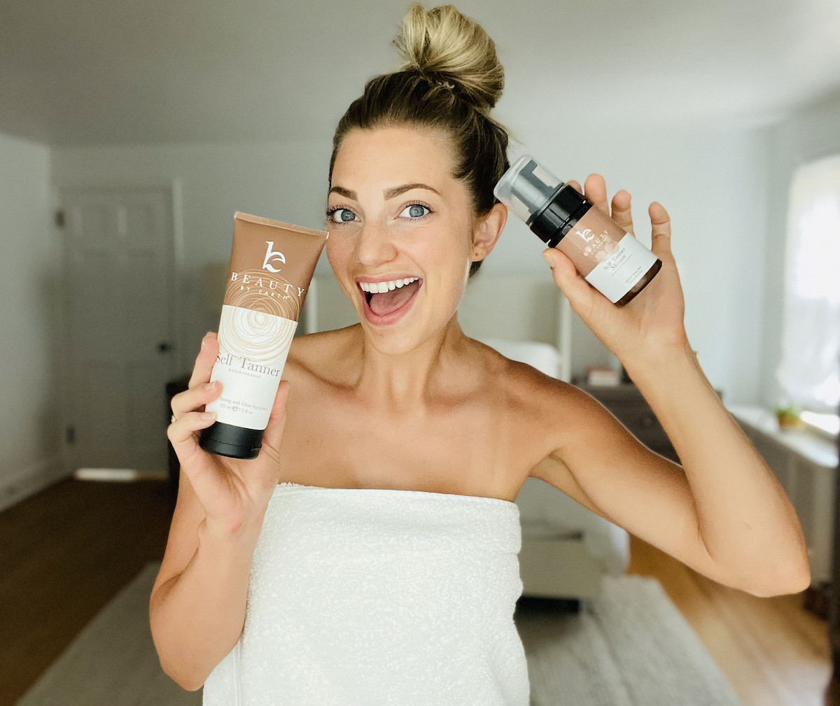 woman wearing white towel holding up beauty products