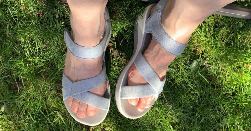 feet on grass wearing gray sandals
