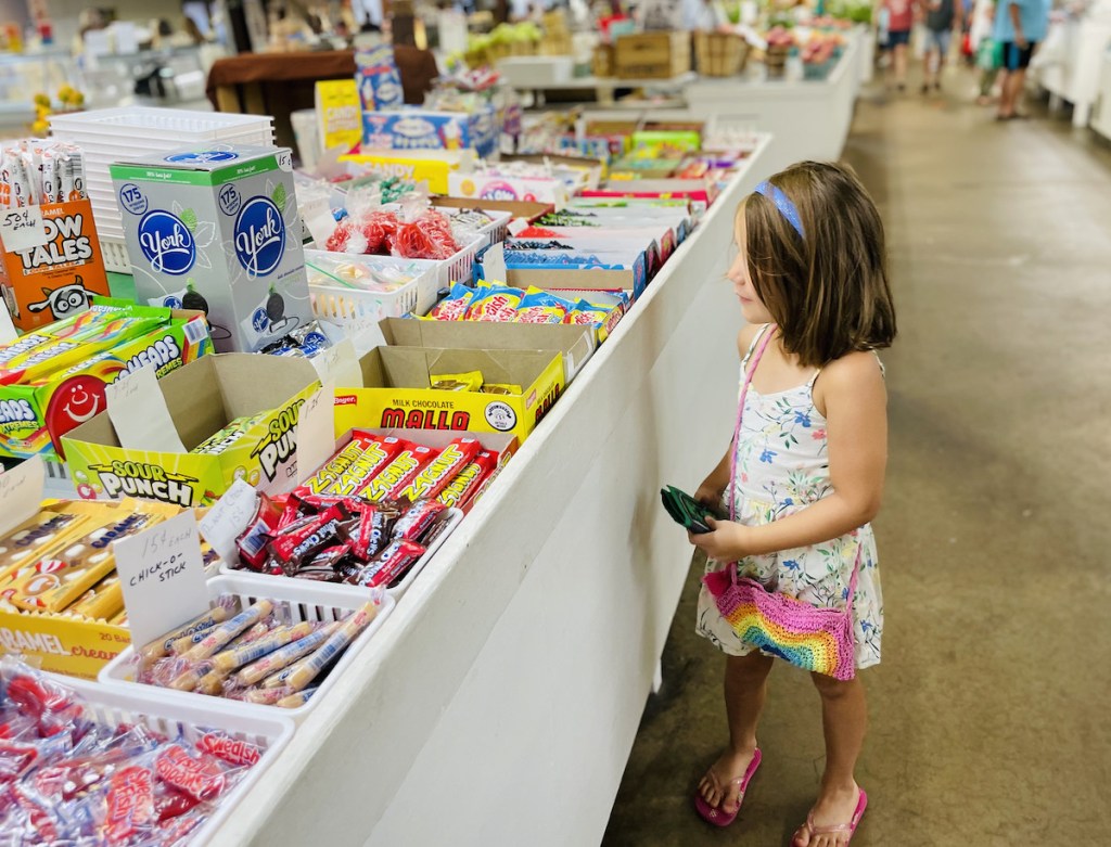 girl looking at farmers market table full of candy