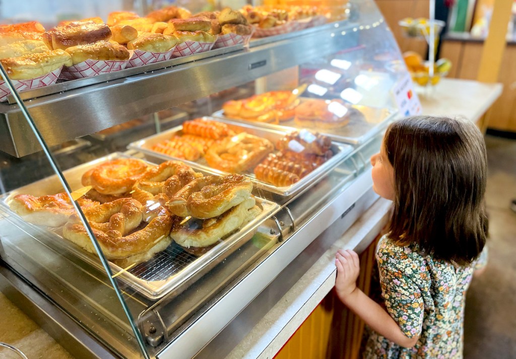 child looking into warming shelf full of soft pretzels