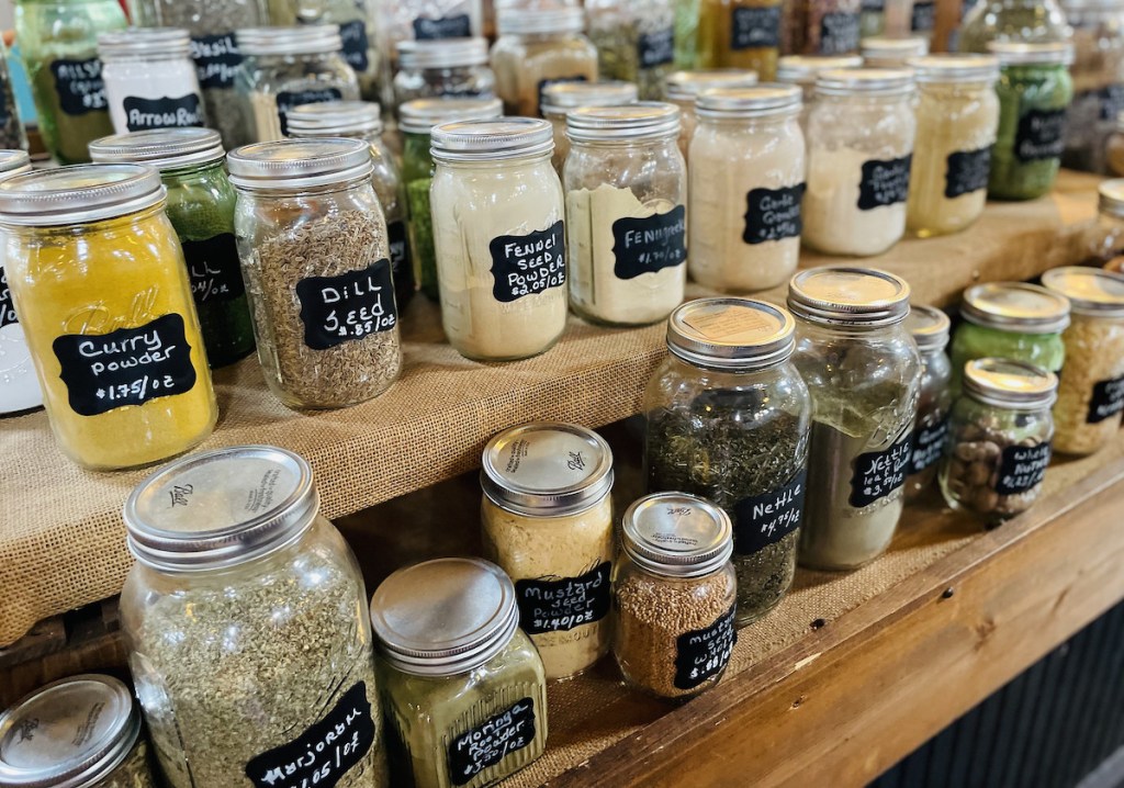 mason jars of spices lined up on wooden burlap covered shelves