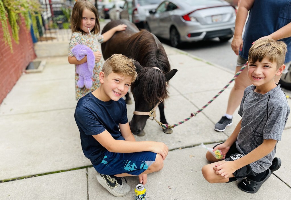 kids on sidewalk petting pony