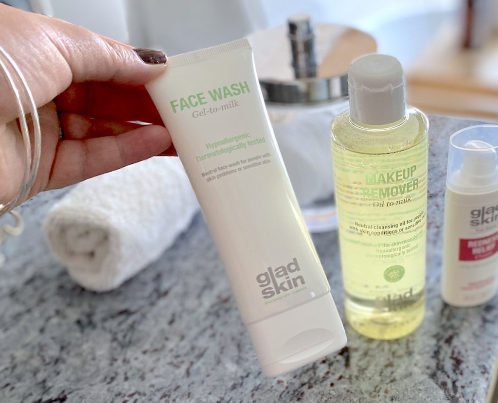 hand holding glad skin face wash and makeup remover on bathroom counter