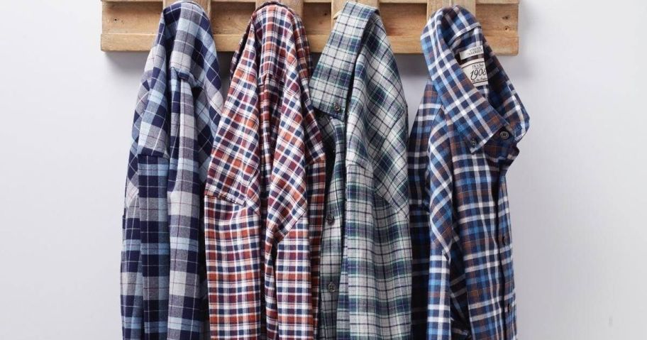 several plaid men's shirts hanging on rack on wall