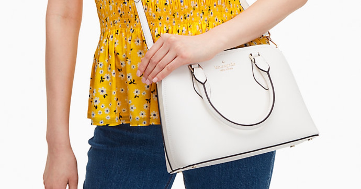 woman in a yellow top and jeans with a white kate spade satchel bag