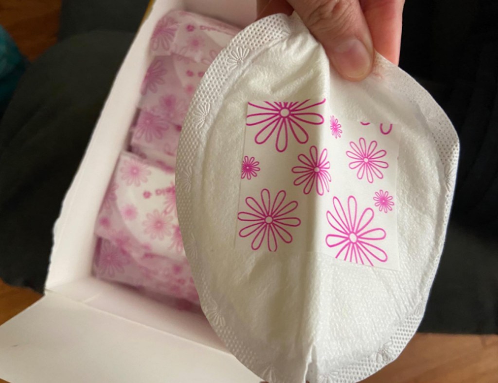 close up of hand holding round breast pad with flower stick on back