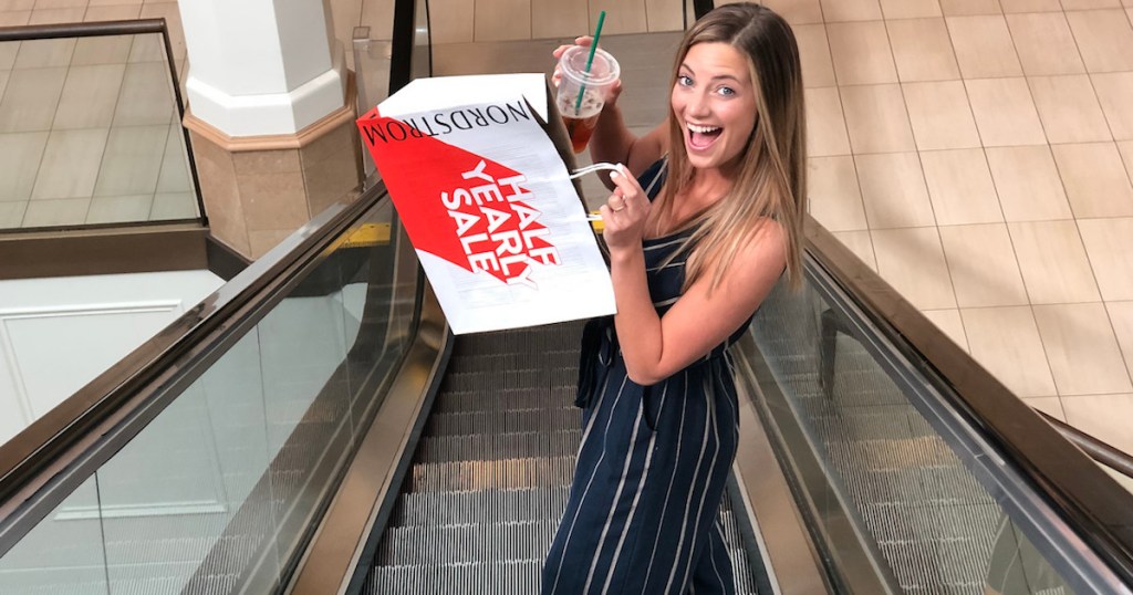 woman holding nordstrom anniversary sale bag while standing on elevator
